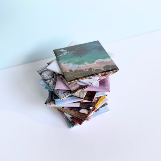 Image shows a stack of square photo magnets piled up.